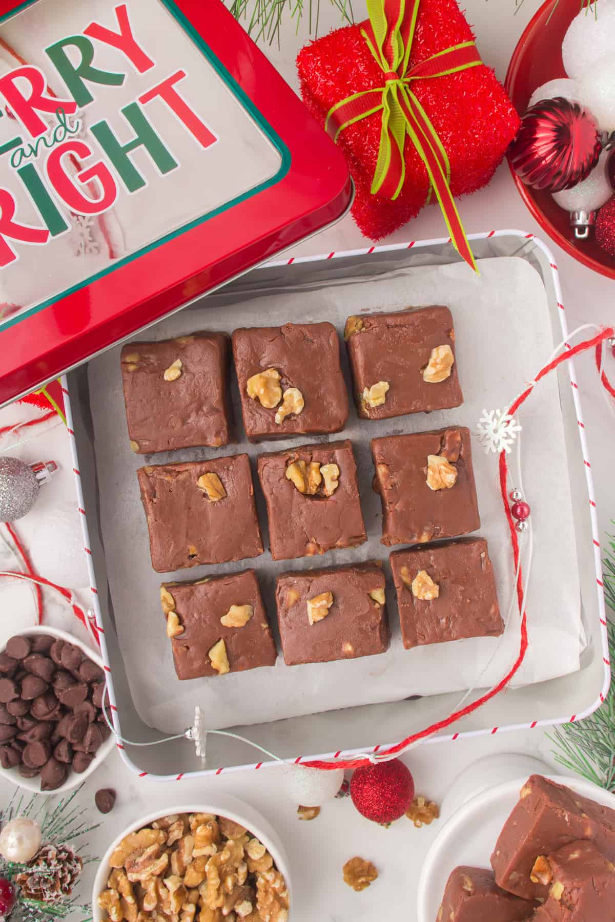 sliced squares of fantasy fudge laid out on a parchment paper lined silver baking dish