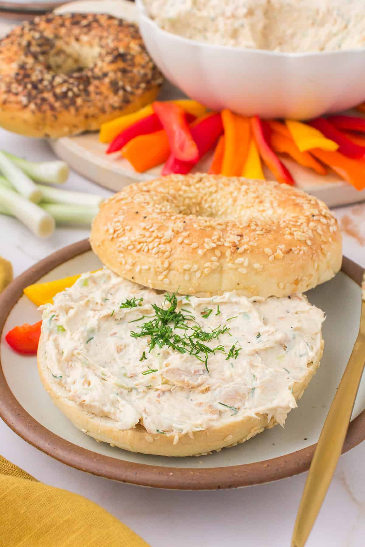 smoked salmon spread on a toasted everything bagel on a decorative gray saucer with fresh dill on top