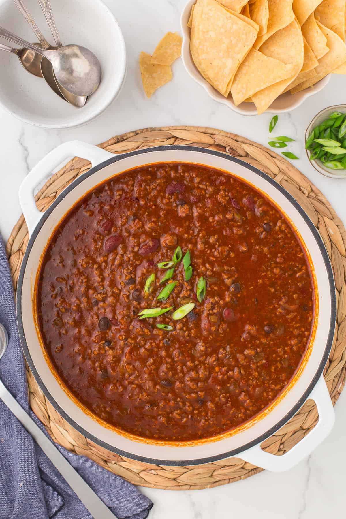 overhead photo showing chili con carne with ground beef in a big white Dutch oven