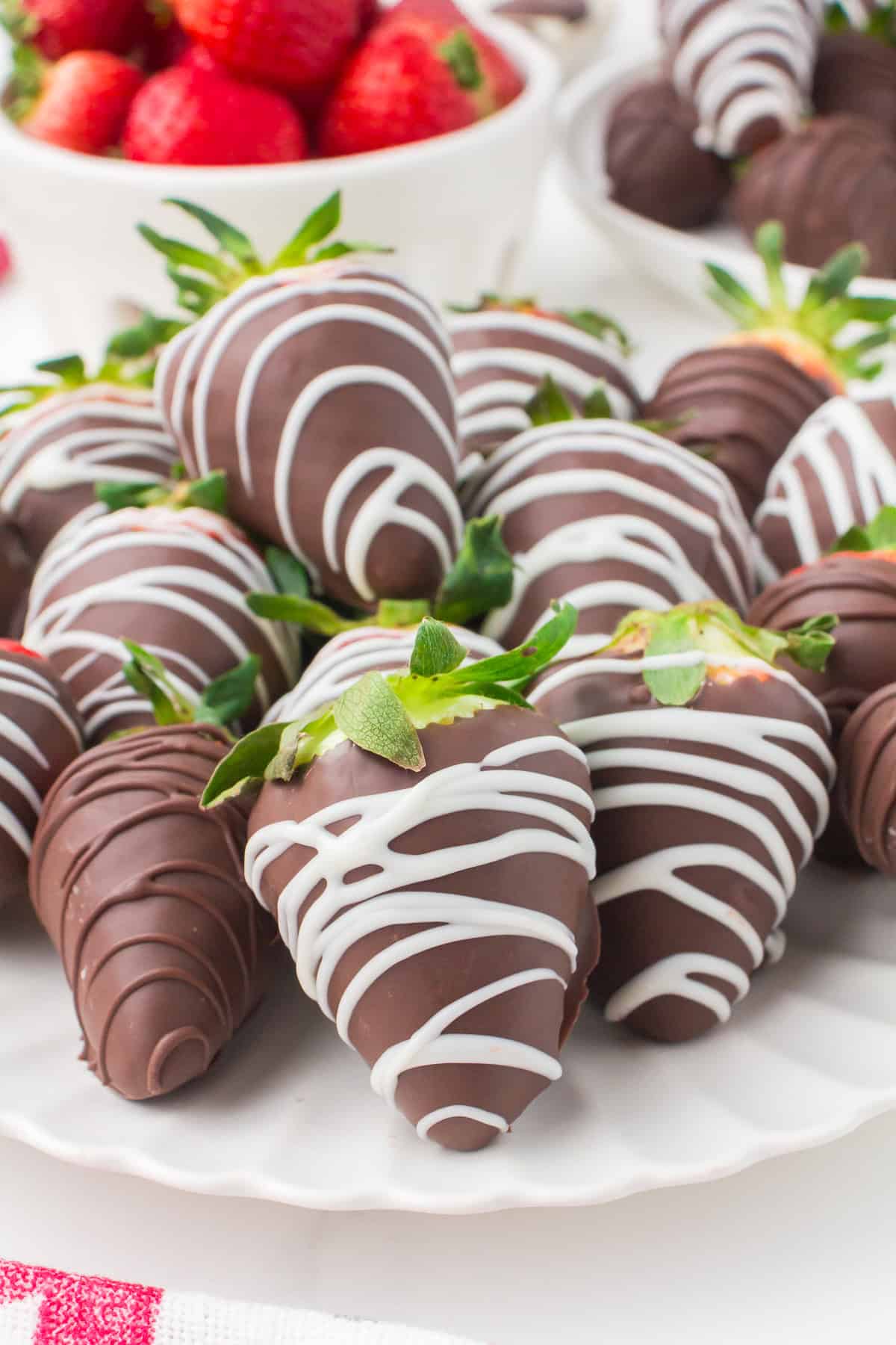 assortment of chocolate covered strawberries with a white chocolate drizzle on a decorative white plate