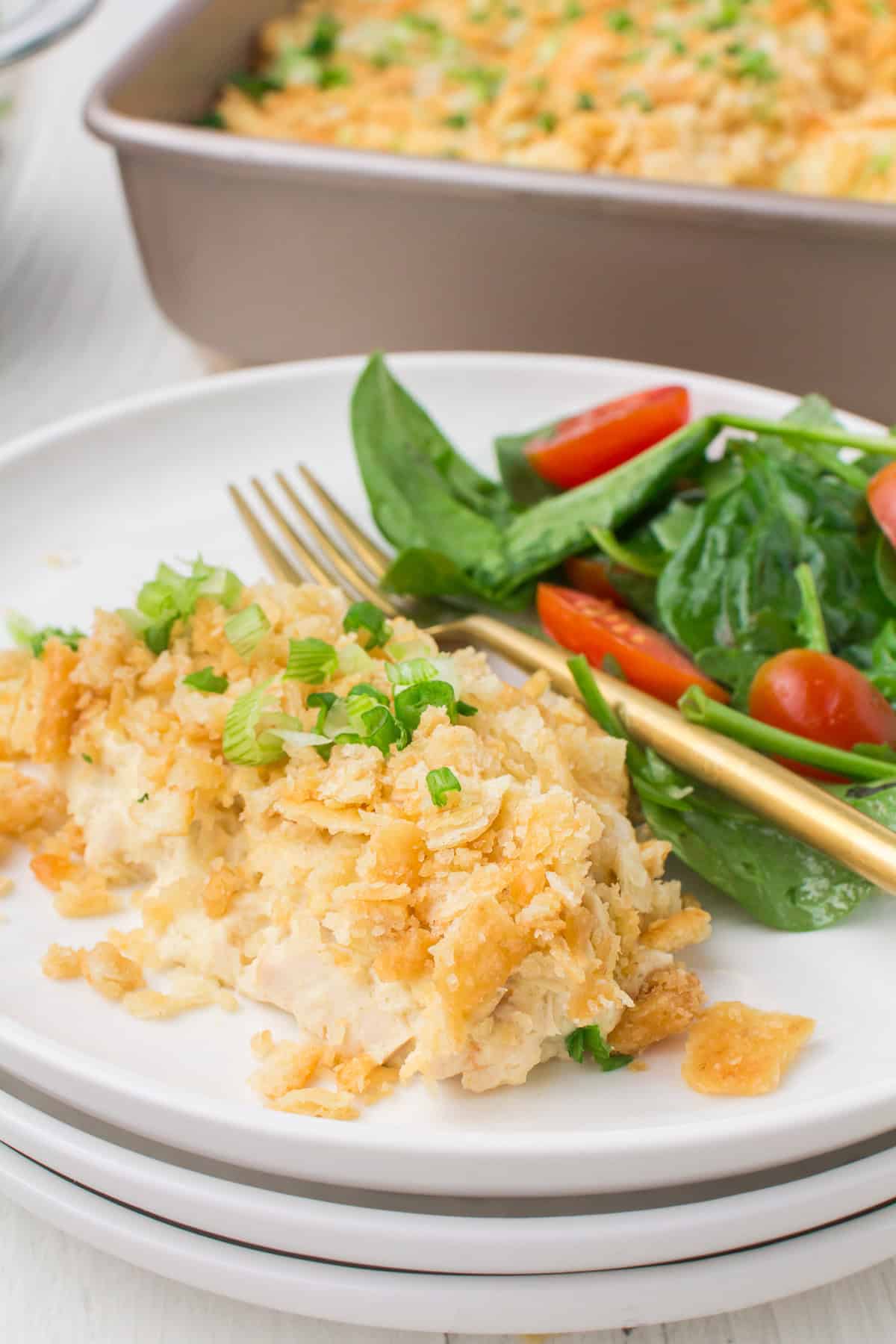chicken casserole with Ritz crackers dishes out on a small white plate with a small salad on the side