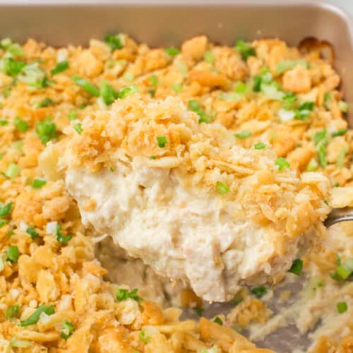 scoop of chicken casserole with Ritz crackers on top over a large square pan full of Ritz cracker chicken casserole