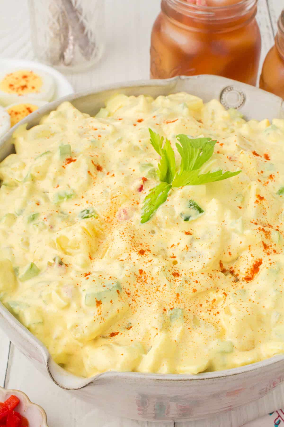 potato deviled egg salad in a small gray bowl with celery leaves on top for garnish