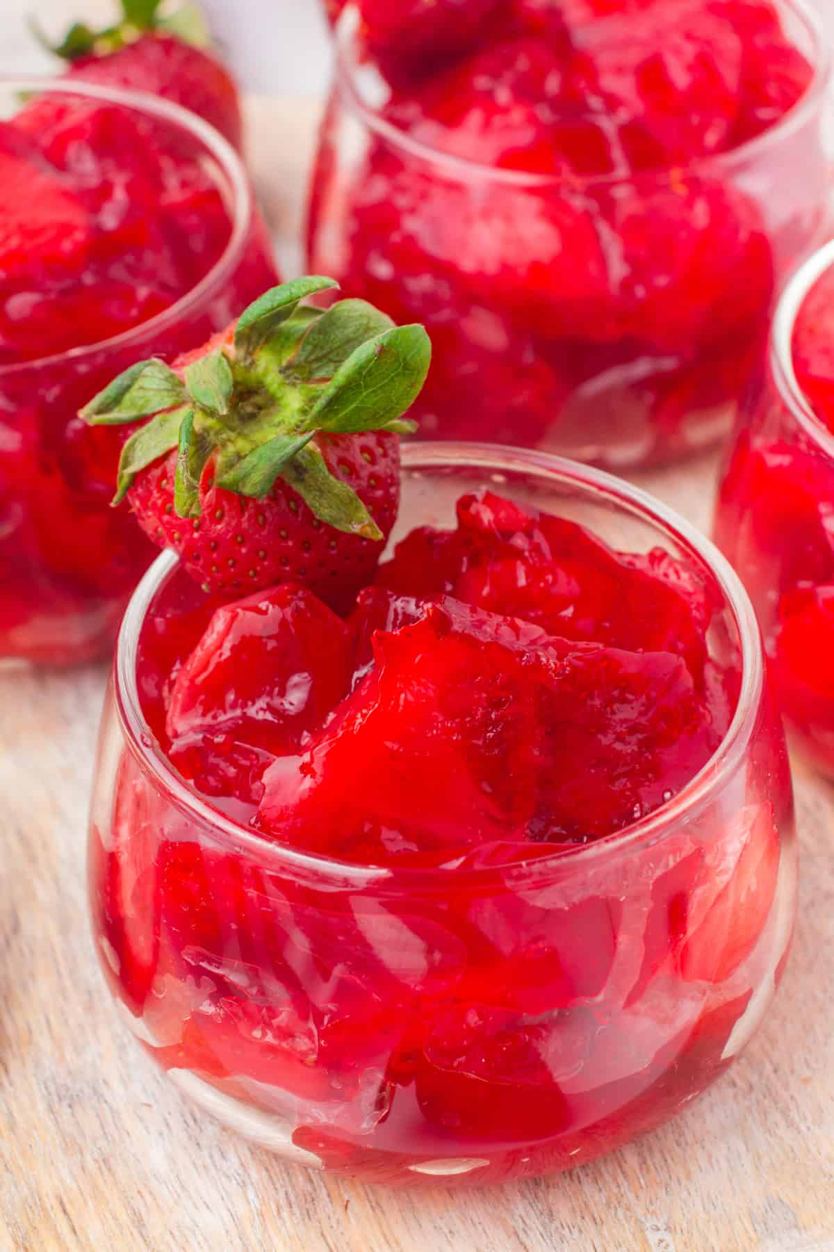 strawberry Jello with fruit in a small glass serving dish with a fresh berry on top
