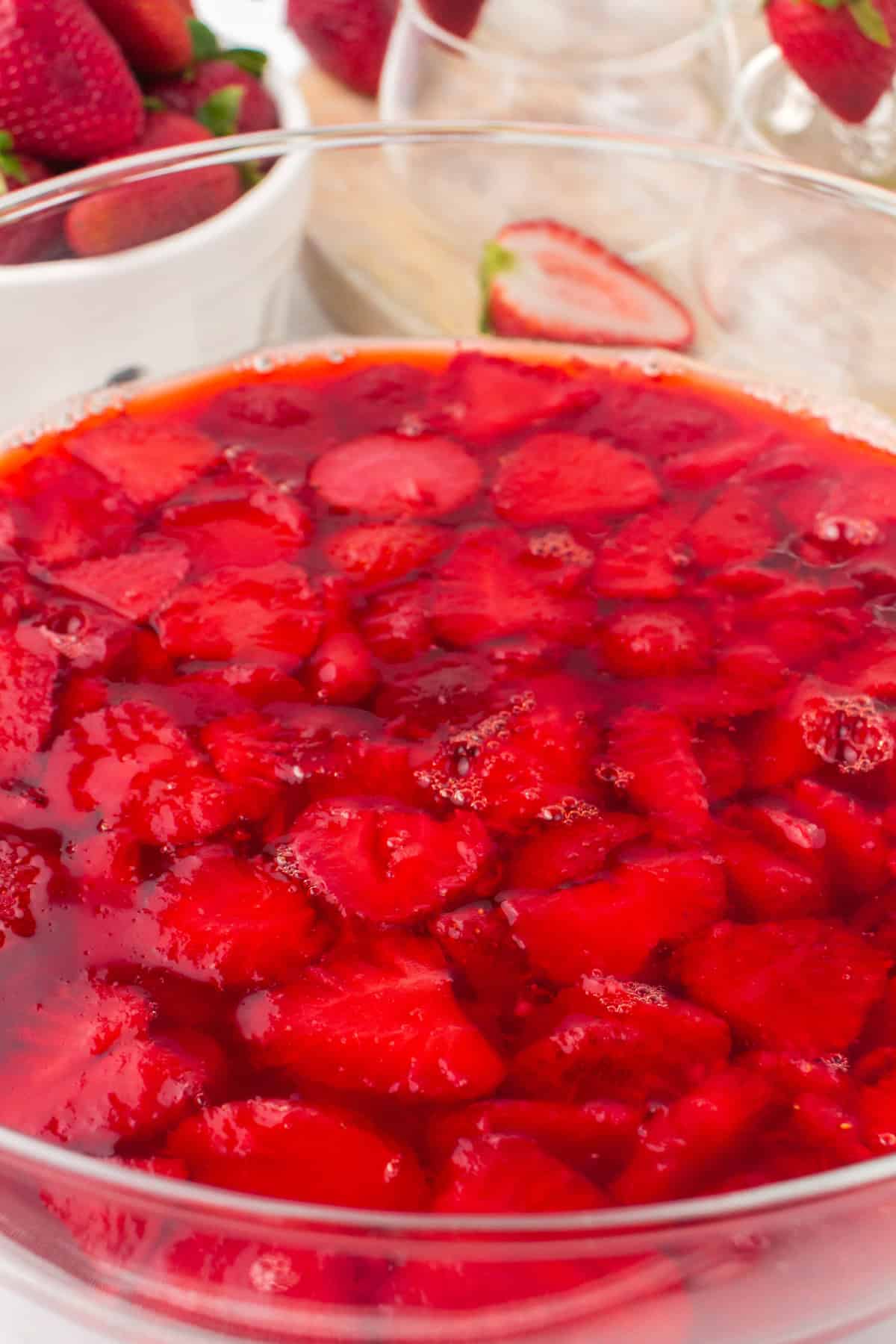 glass bowl full of strawberry Jello with fruit suspended inside