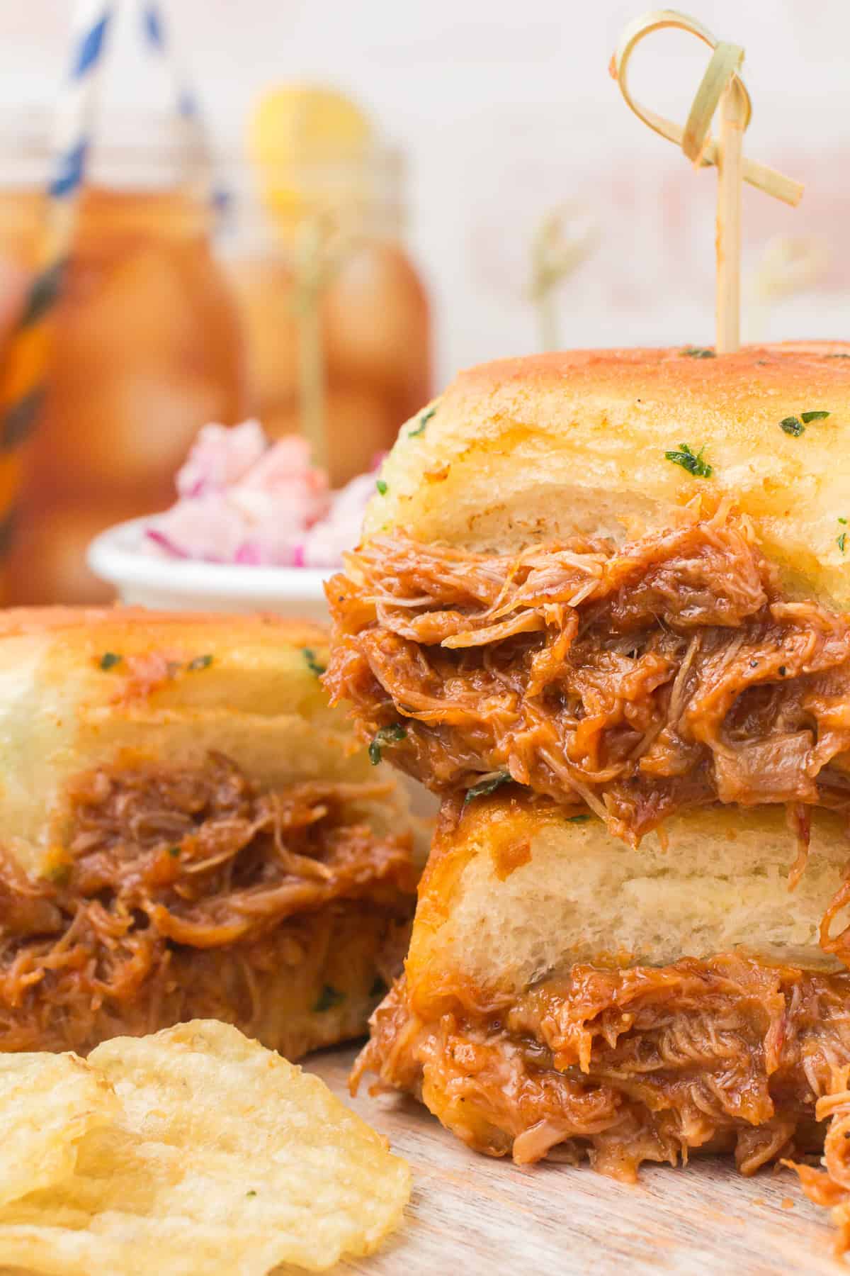 bbq chicken sliders on wood cutting board with iced tea in the background