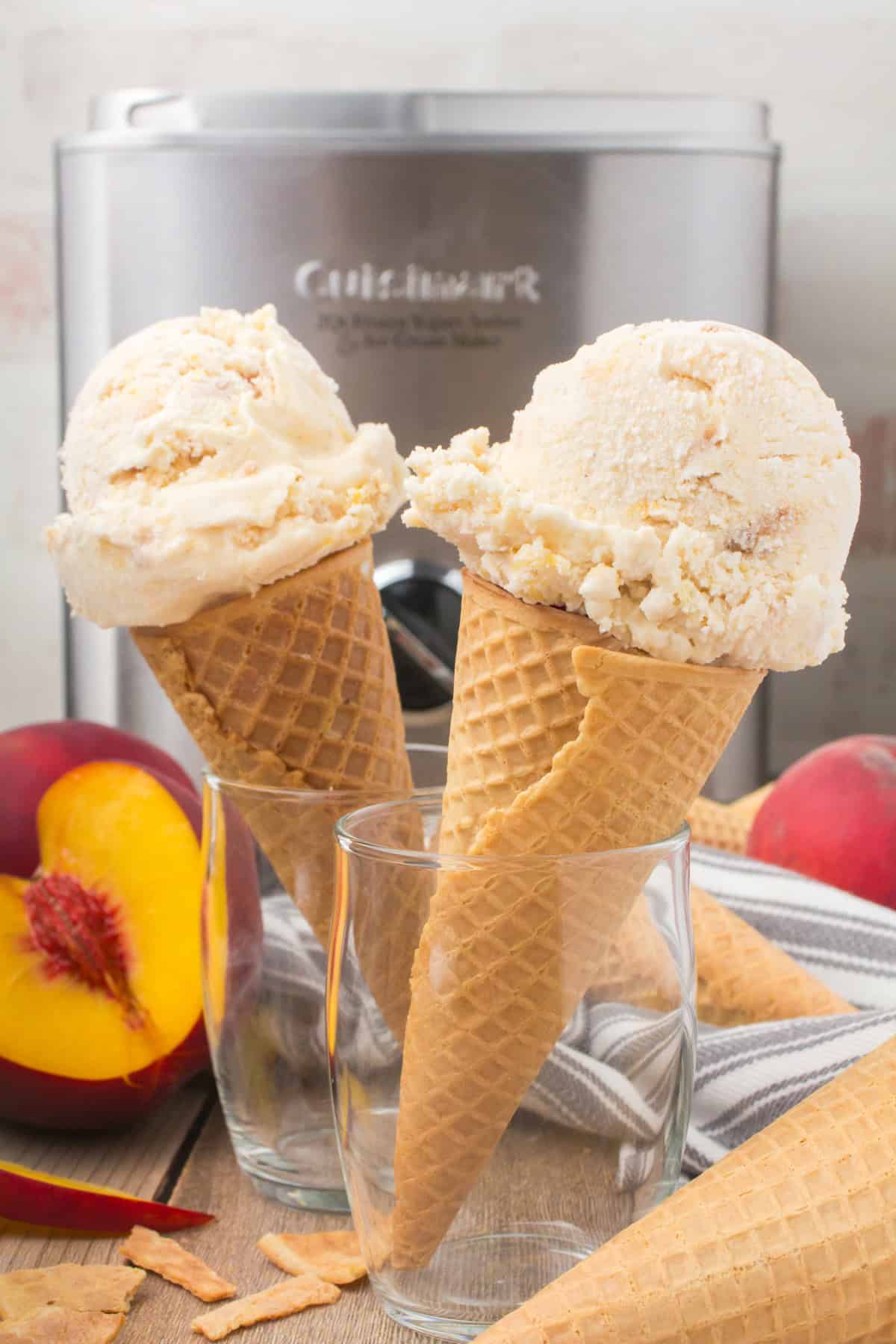 peach cobbler ice cream in waffle ice cream cones with an ice cream maker in the background