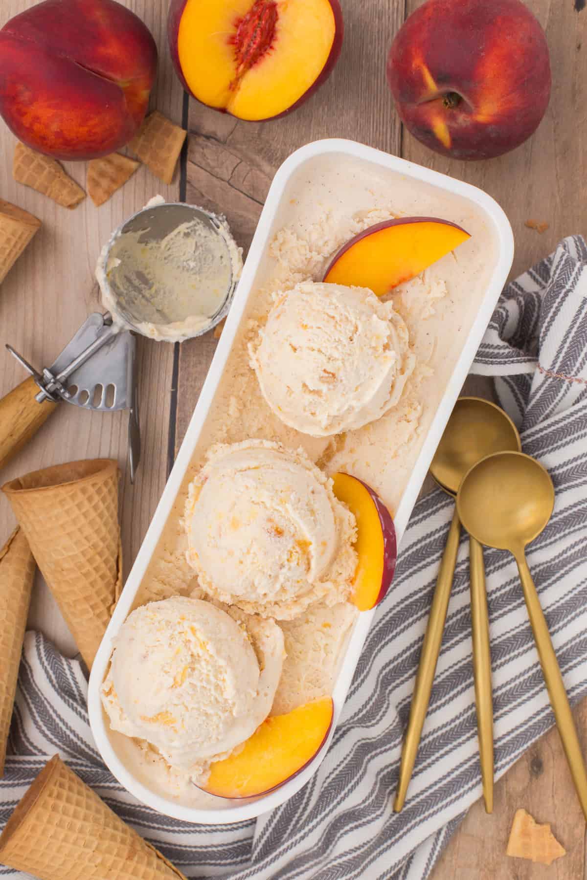 peach cobbler ice cream in an ice cream tub with fresh peach slices on top