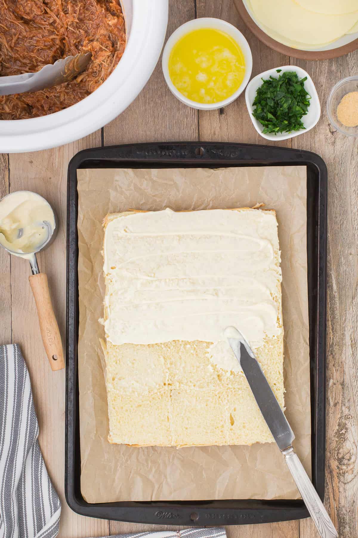 spread mayo on bottom layer of sliced Hawaiian rolls on baking sheet
