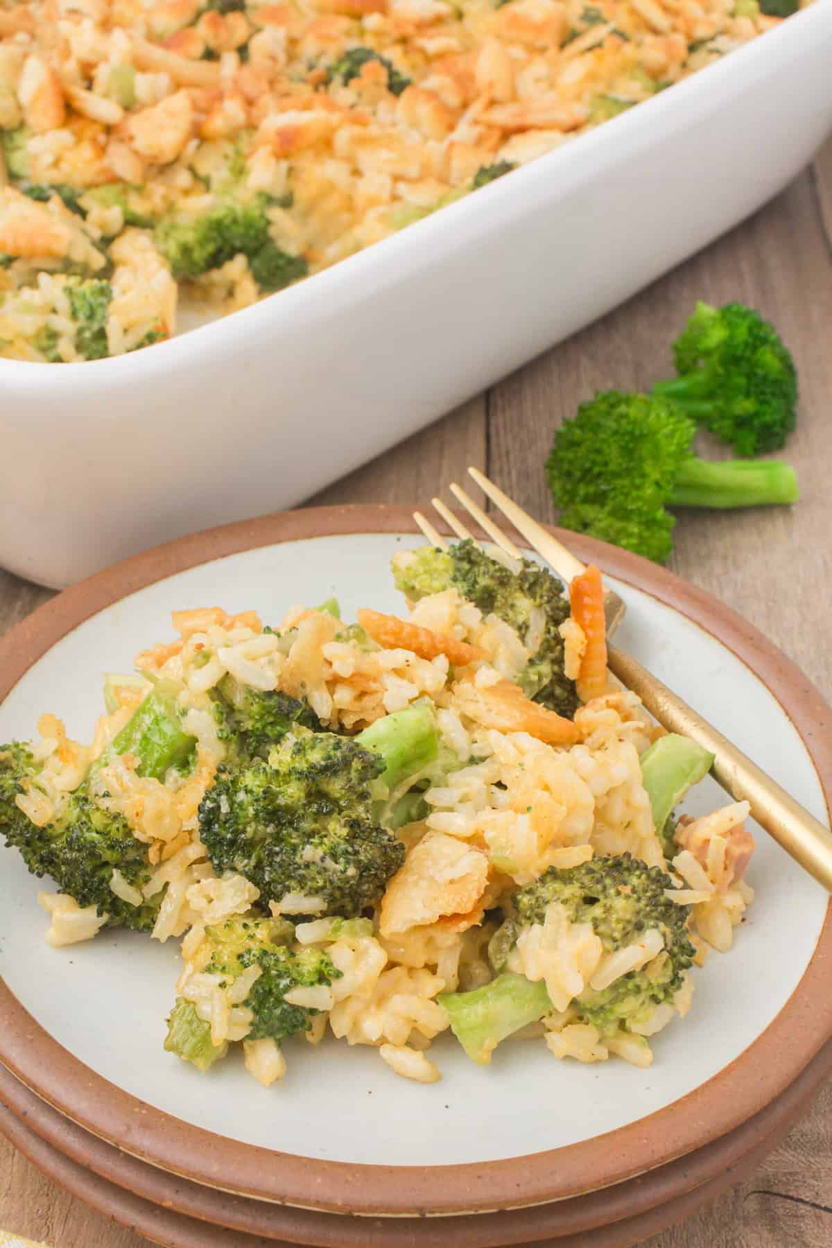 small decorative plate of broccoli and cheese rice casserole with a full casserole pan in the background