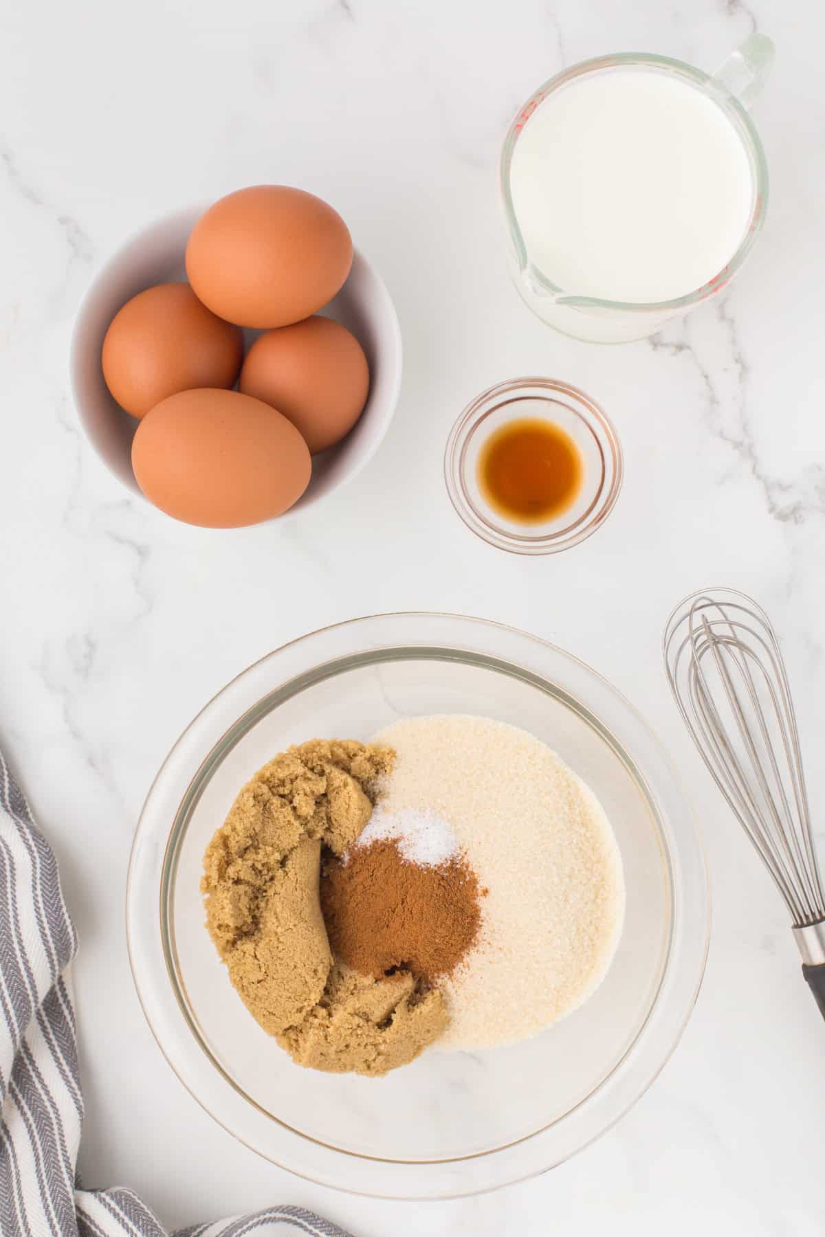 bread pudding egg custard mix in a small glass mixing bowl with a whisk setting off to the side