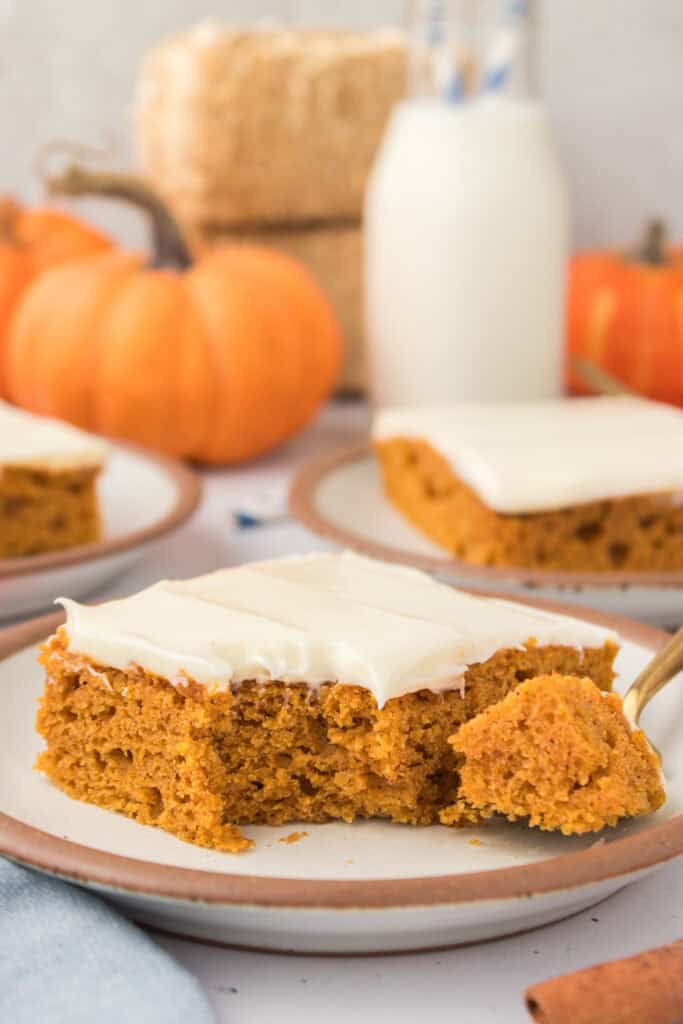 pumpkin bars with cream cheese frosting on a small white plate with a bite taken out