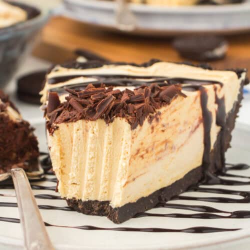 wedged slice of classic no bake peanut butter pie drizzled with chocolate syrup and garnished with chocolate shavings on a small plate