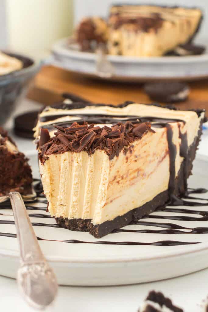 wedged slice of classic no bake peanut butter pie drizzled with chocolate syrup and garnished with chocolate shavings on a small plate