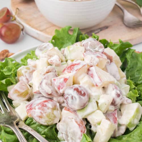 classic Waldorf salad served up on a bed of green leaf lettuce with a small bowl in the background
