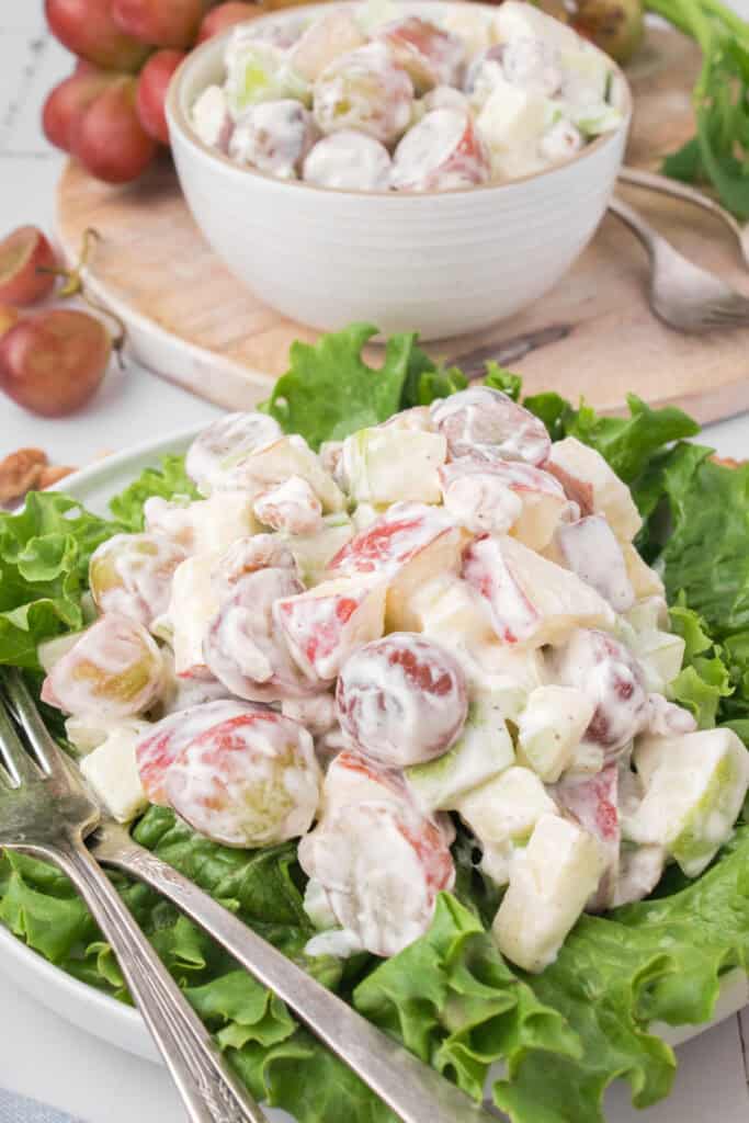 classic Waldorf salad served up on a bed of green leaf lettuce with a small bowl in the background