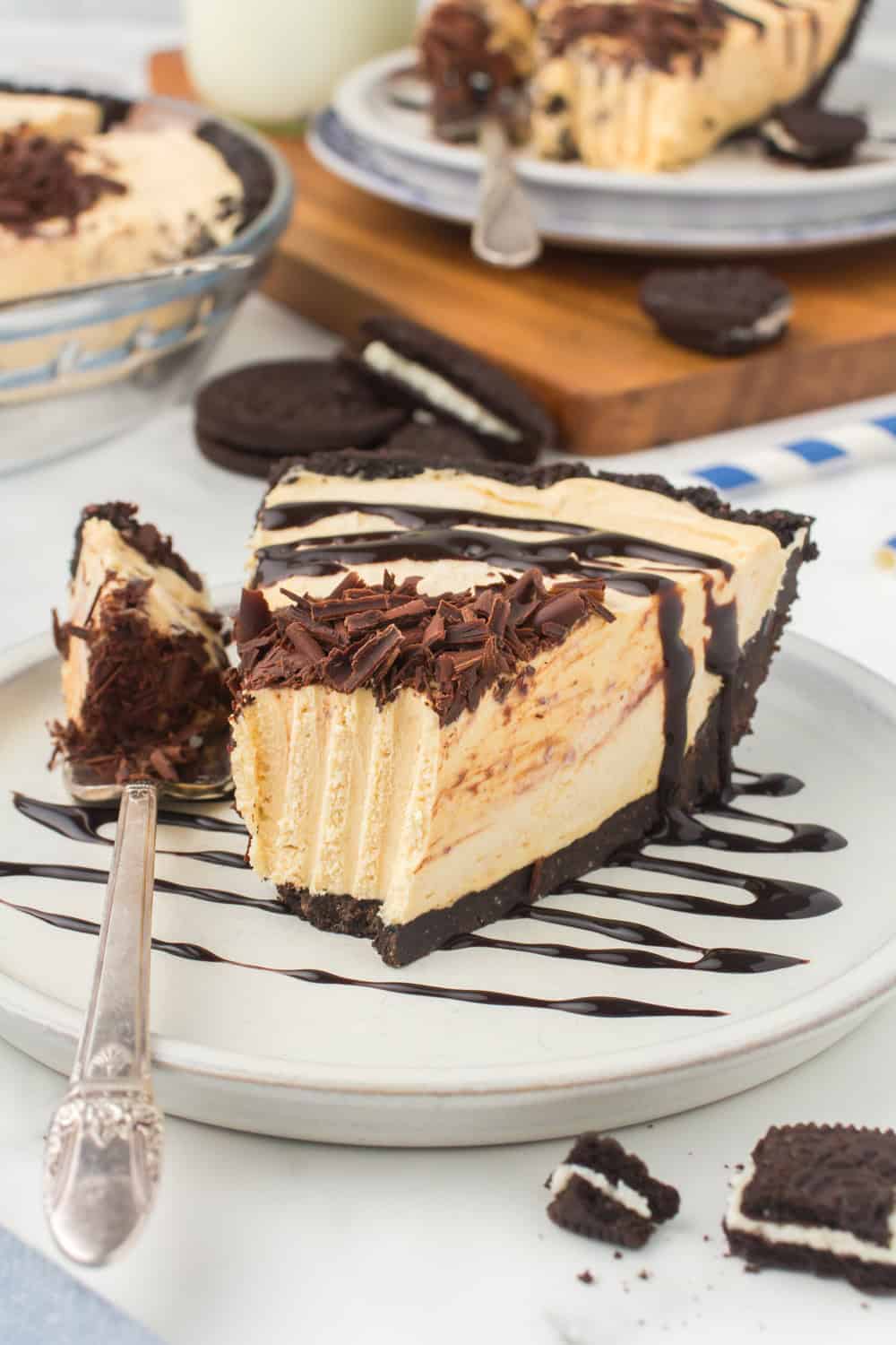 wedged slice of creamy no bake peanut butter pie drizzled with chocolate syrup and garnished with chocolate shavings on a small plate