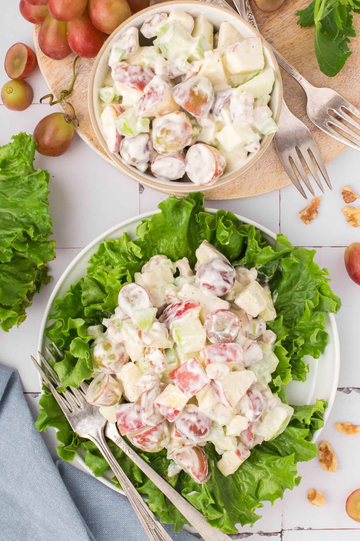 overhead shot showing old-fashioned Waldorf salad served up on a bed of green leaf lettuce with a bowl in the background